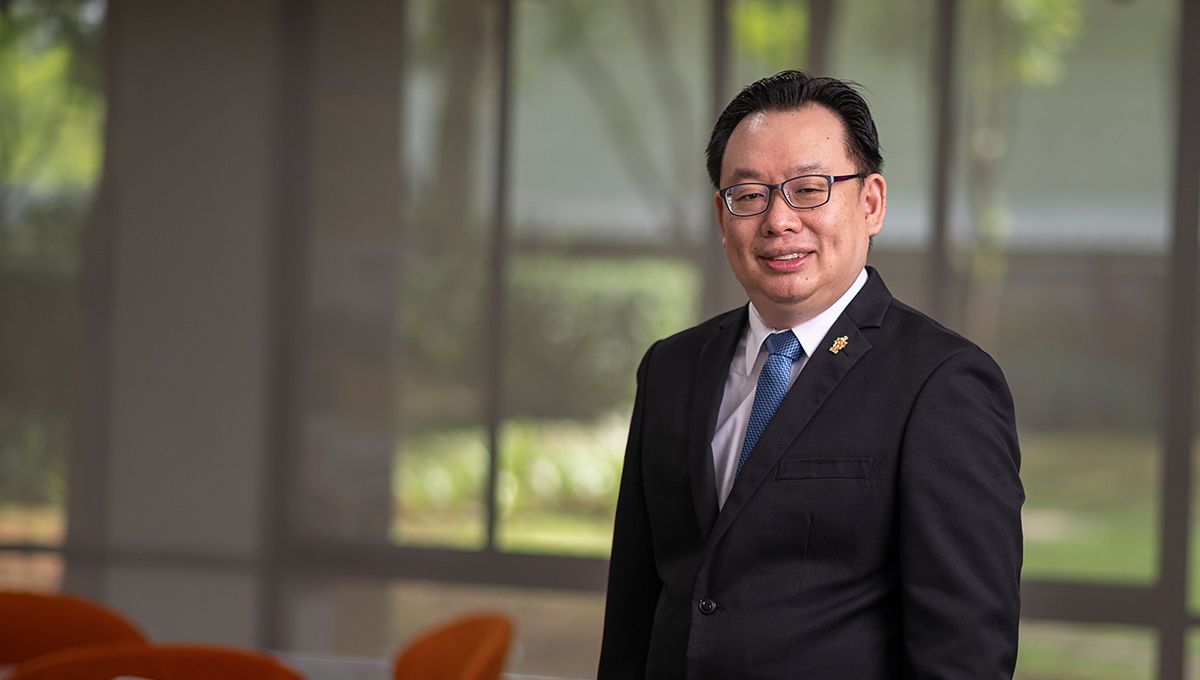 A professional man wearing a suit and glasses, looks to camera. 
