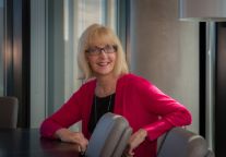 Joanne Williams sitting at a table looking at the camera.