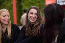 three female students smiling and laughing outside on campus