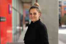 Blond female student wearing a black jumper looking at the camera