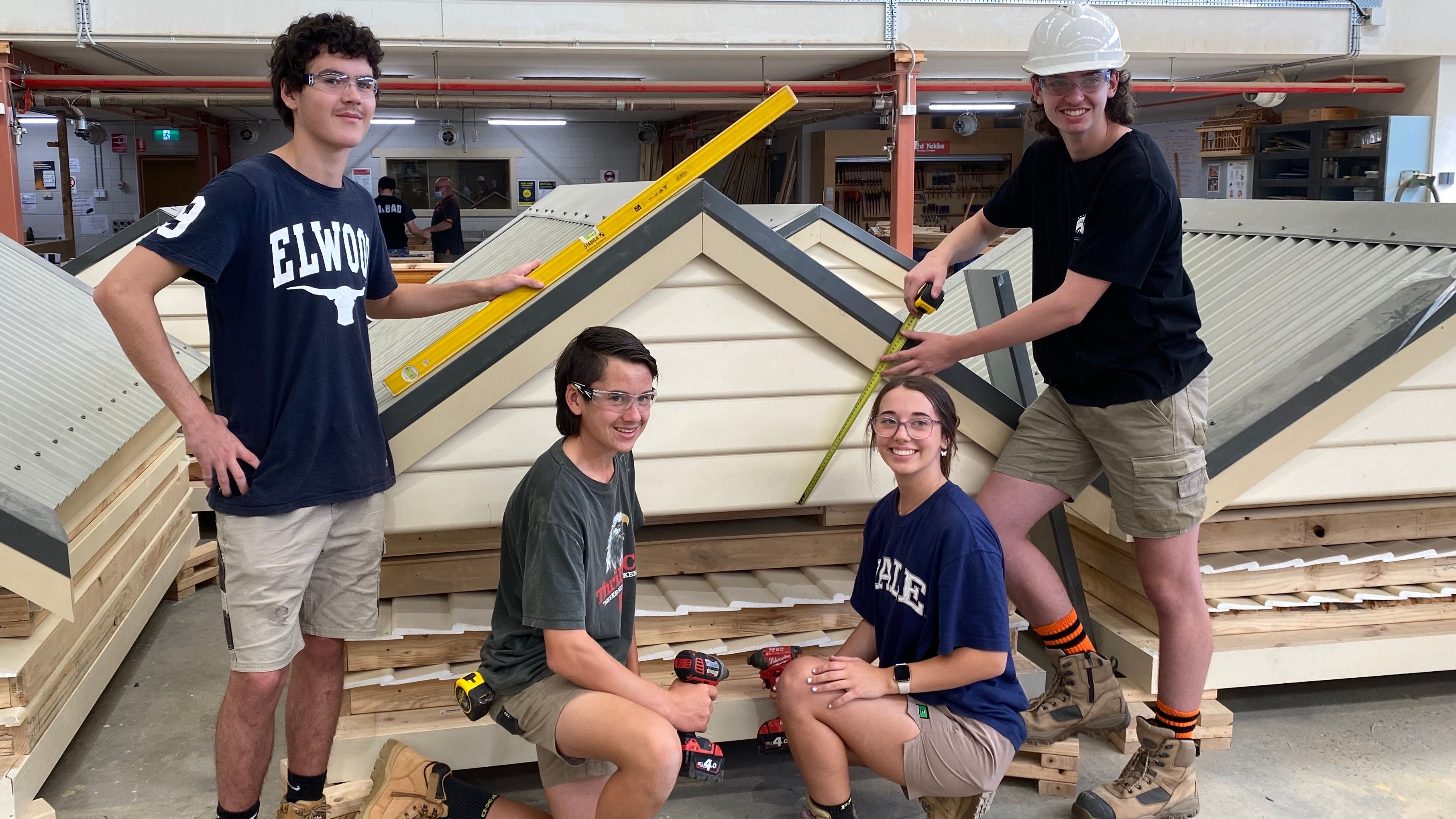 Vet Studnets holding tools and building equipment in front of tool sheds built for bushfire affected communities