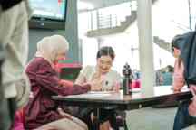 Two international students sit at a desk and work through an assignment on campus