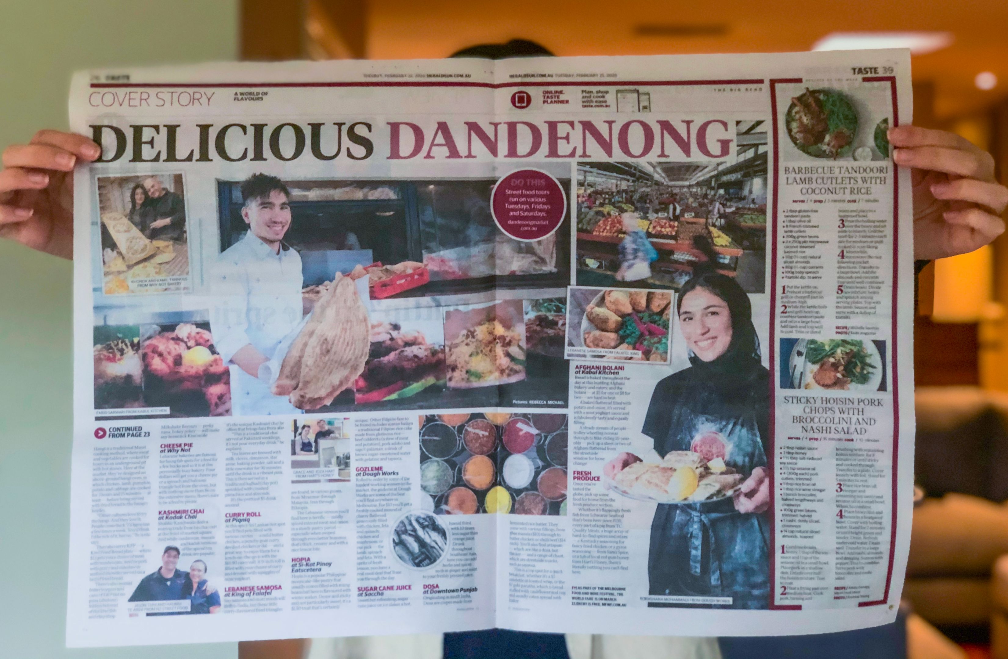 A person holding up an open newspaper in front of them. 