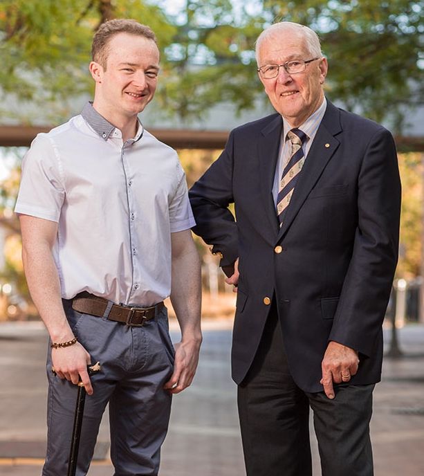Matt Ward stands aided by cane to the left of Keith Irvine in suit attire