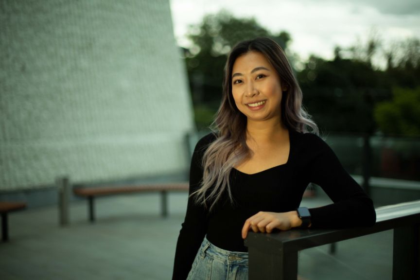 Young woman standing against railing smiling
