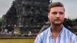 Man looking to the side of the camera with a temple in the background