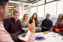 Group Of Students In Library Collaborating On Project