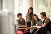 undergrad students at a desk studying and socialising