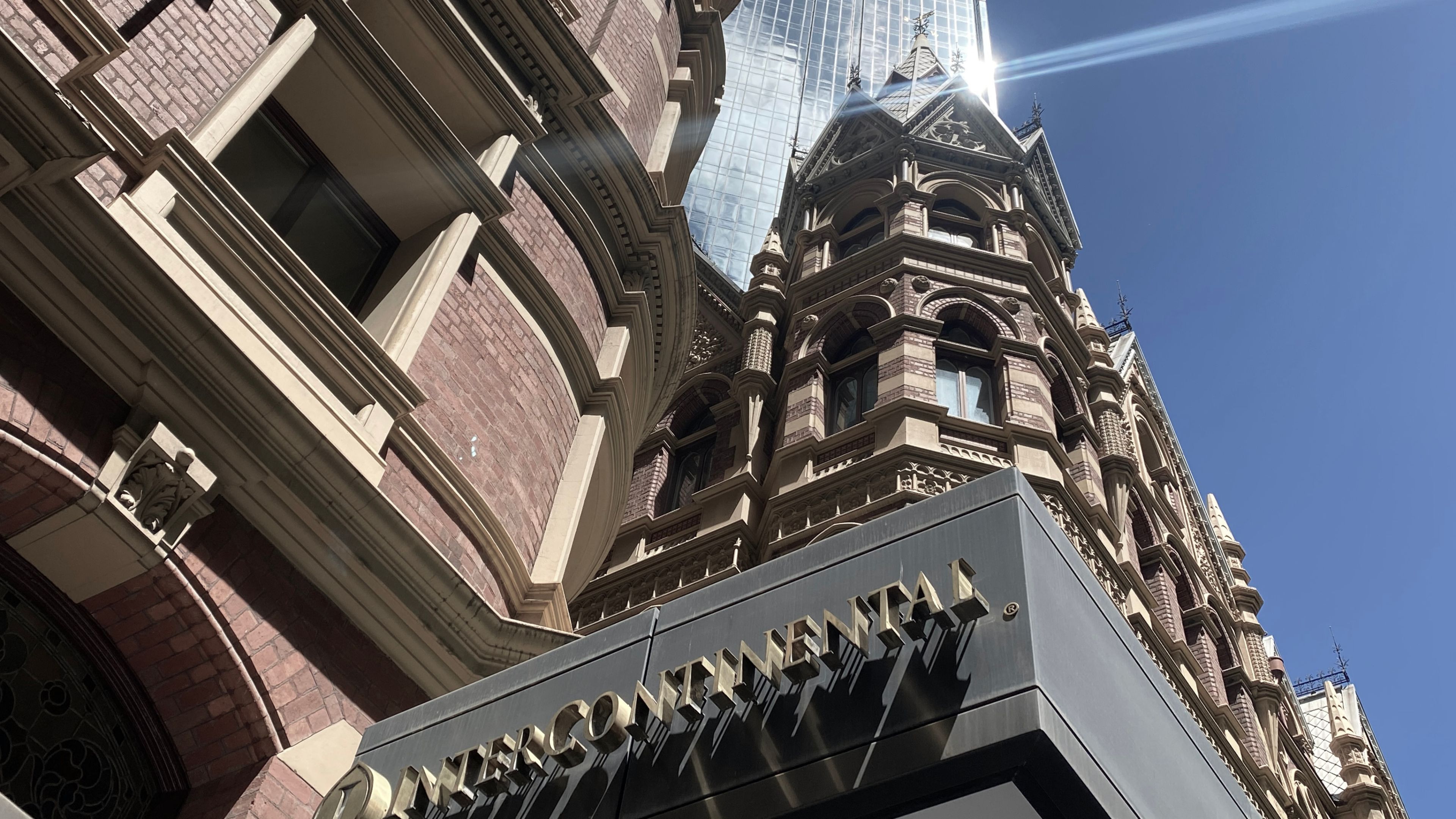 Looking up at the Intercontinental Hotel red brick building with a skyscraper in the background.
