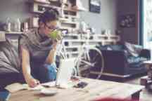 Young Caucasian woman working and drinking coffee at home
