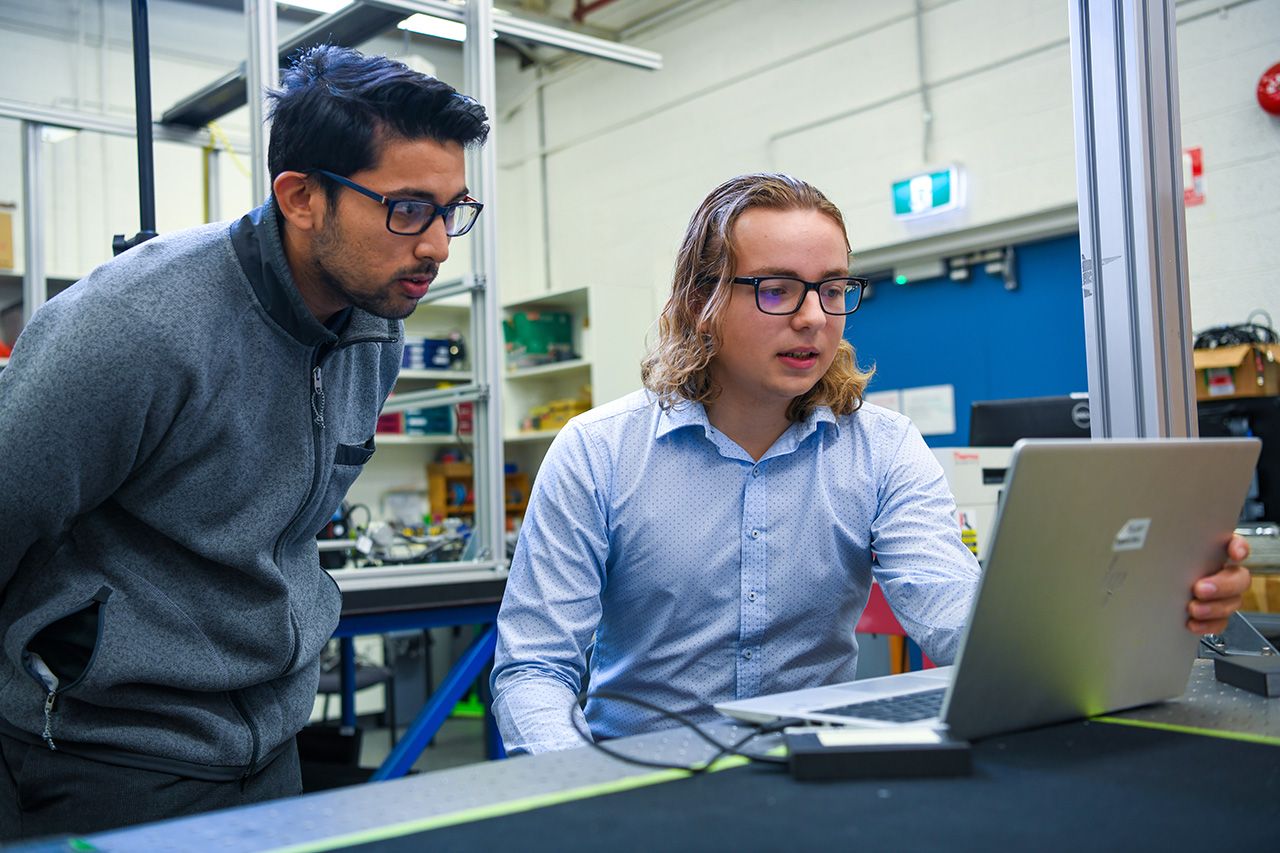 student working with someone on laptop