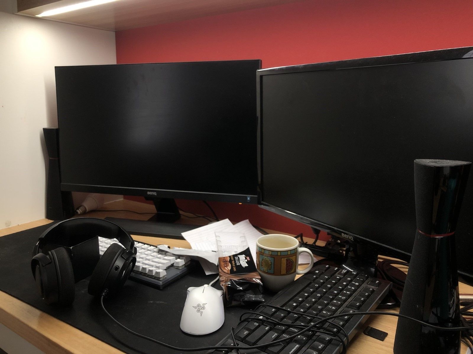 Lewis’s desk, complete with two large computer monitors, over-ear headphones, a half-eaten packet of Tim Tams and an empty coffee mug.