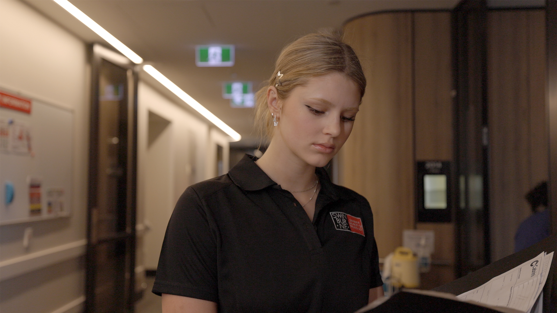 Nursing student at Cabrini hospital standing in the hallway and looking down at a folder