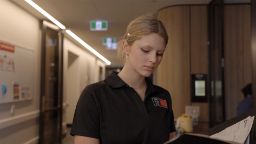 Nursing student at Cabrini hospital standing in the hallway and looking down at a folder