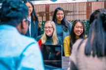 Group of students around a table socialising and laughing 