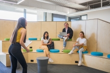 Group of 4 students sitting and studying together, one presenting / lecturing , in the SPW building.