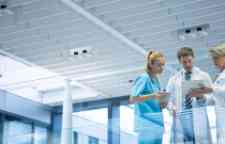 Medical team discussing over digital tablet in corridor.