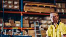 Young male tradesman at work in a factory warehouse.