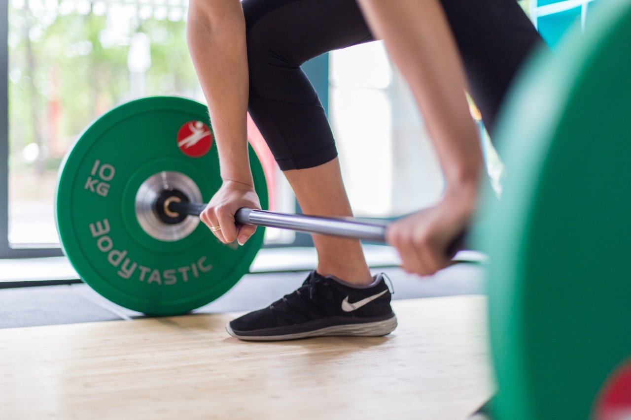 Student exercises in the gym about to lift green weights 