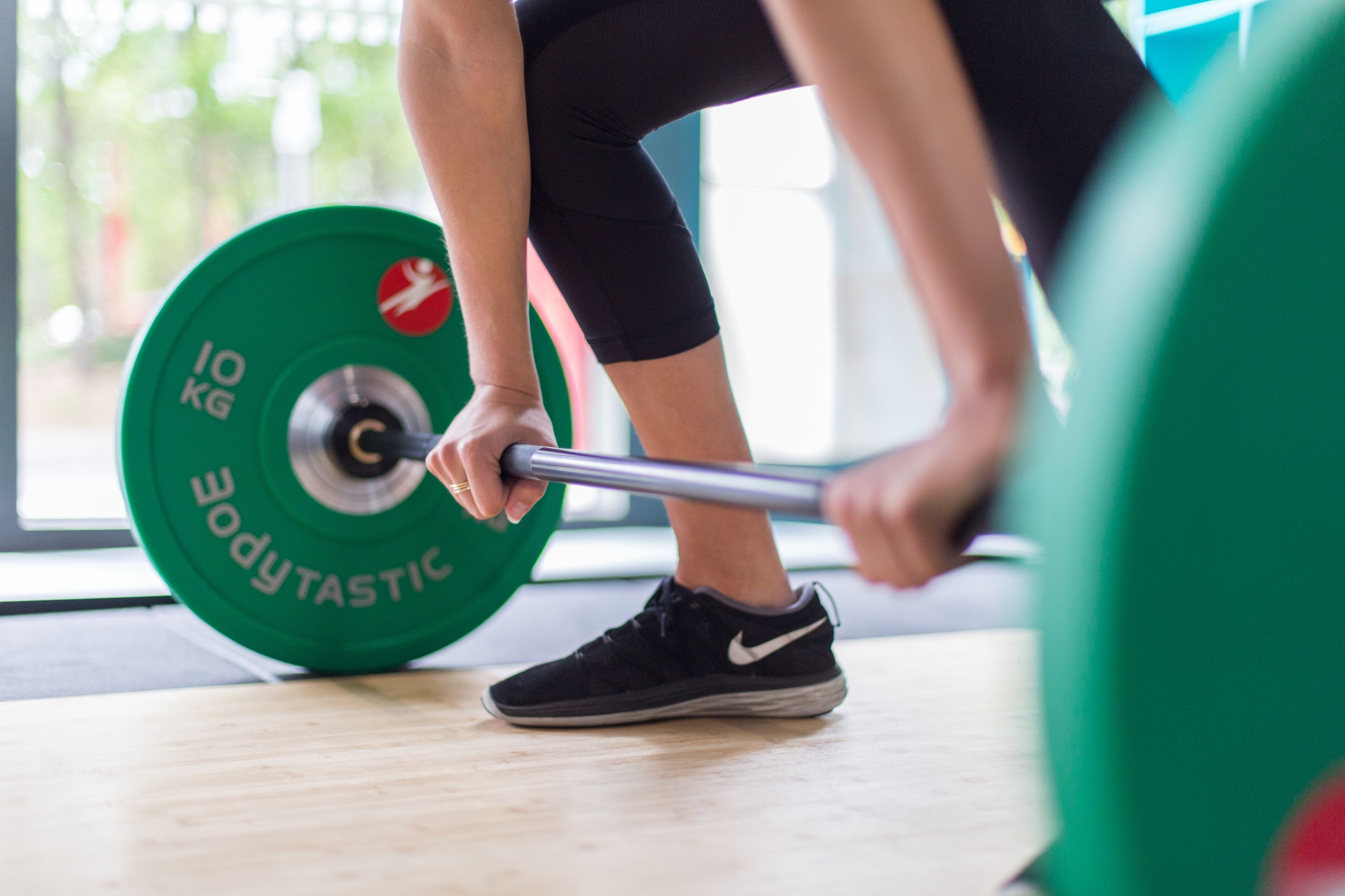 Student exercises in the gym about to lift green weights 