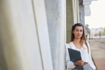 Female student smiling and leaning against wall in AMDC sky garden
