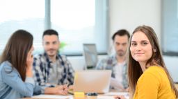A group of students gathering around a desk in a classroom